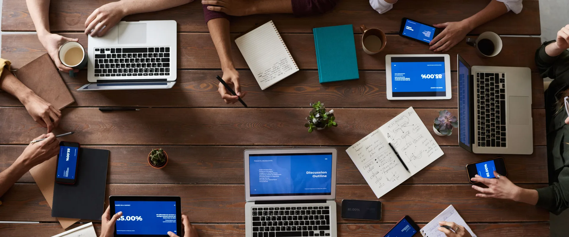 Laptops, tablets, and phones arranged on a table during a business meeting